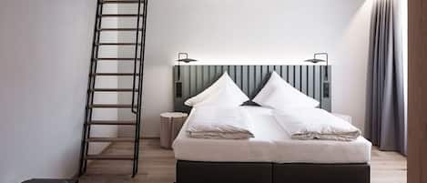 A modern bedroom with a bed, a ladder, a bedside table, and a headboard.