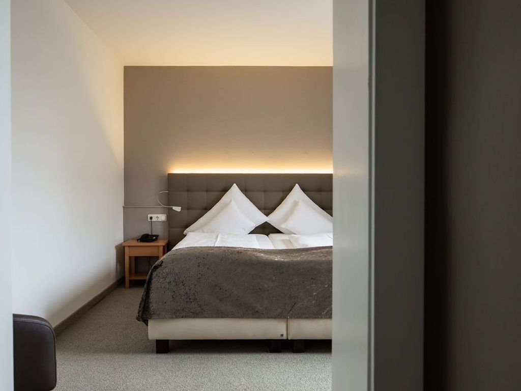 Un dormitorio con cama, mesita de noche, lámpara y una lámpara de pared.