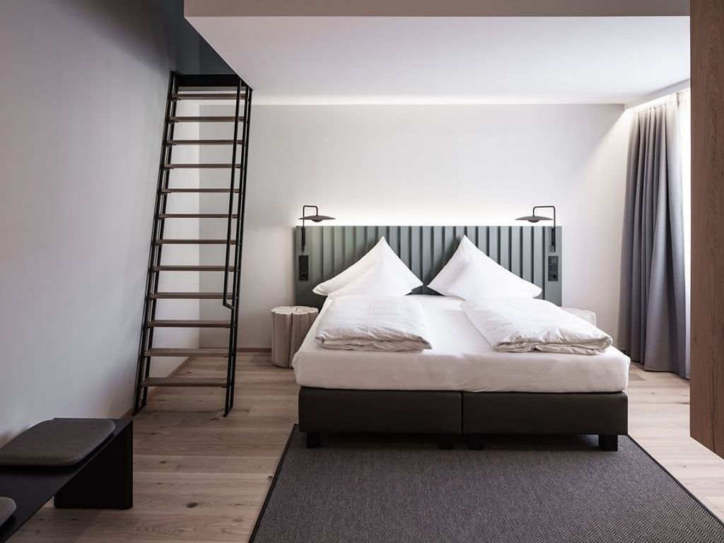 Ein modernes Schlafzimmer mit Bett, einer Wendeltreppe, einem Nachttisch und einer Kopfteil.