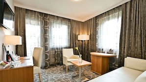 A hotel room with a bed, a desk, a chair, a small table with a vase, and two lamps. - Double Classic Plus - Hotel Goldenes Schiff (Bad Ischl)