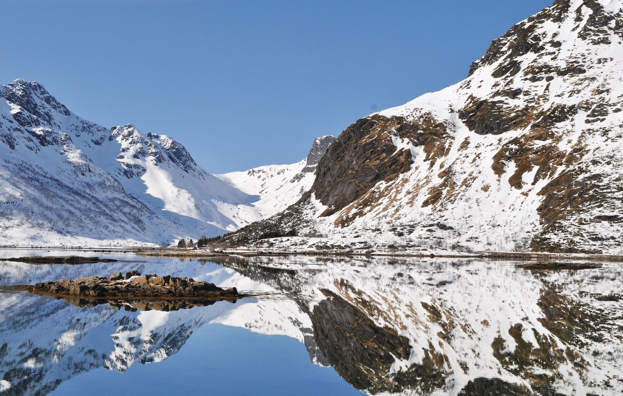 Un paysage de montagne avec des sommets enneigés et un lac paisible qui reflète le paysage environnant.