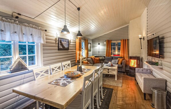 A cozy cabin interior with a dining area, seating, and a fireplace.