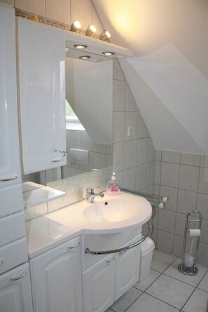 Une salle de bain moderne avec un lavabo blanc, un meuble-lavabo et des armoires.