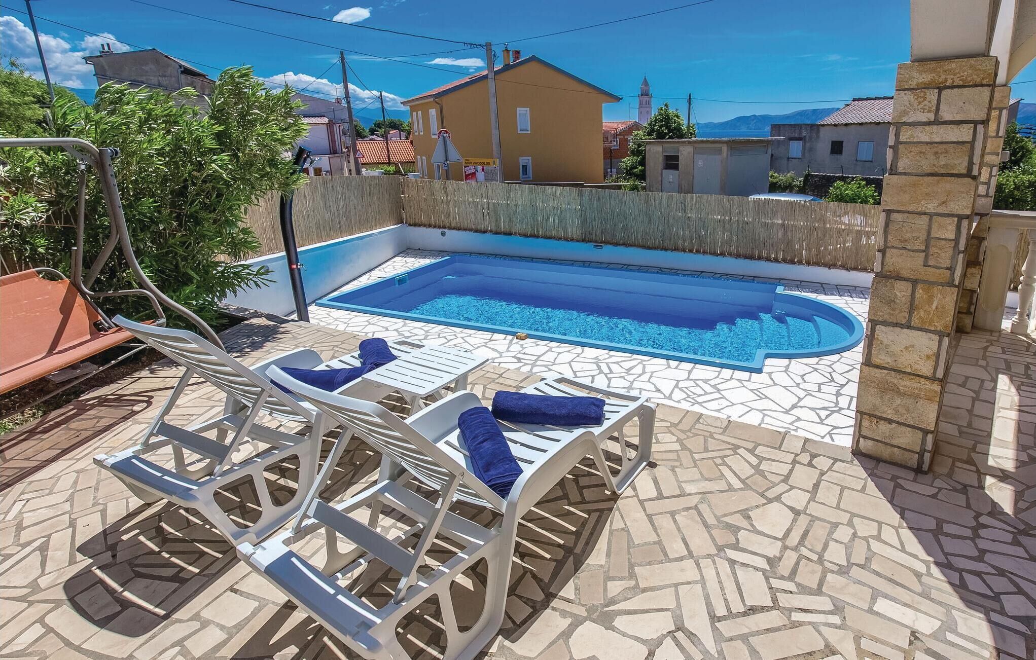 A swimming pool with lounge chairs and a stone-tiled deck.