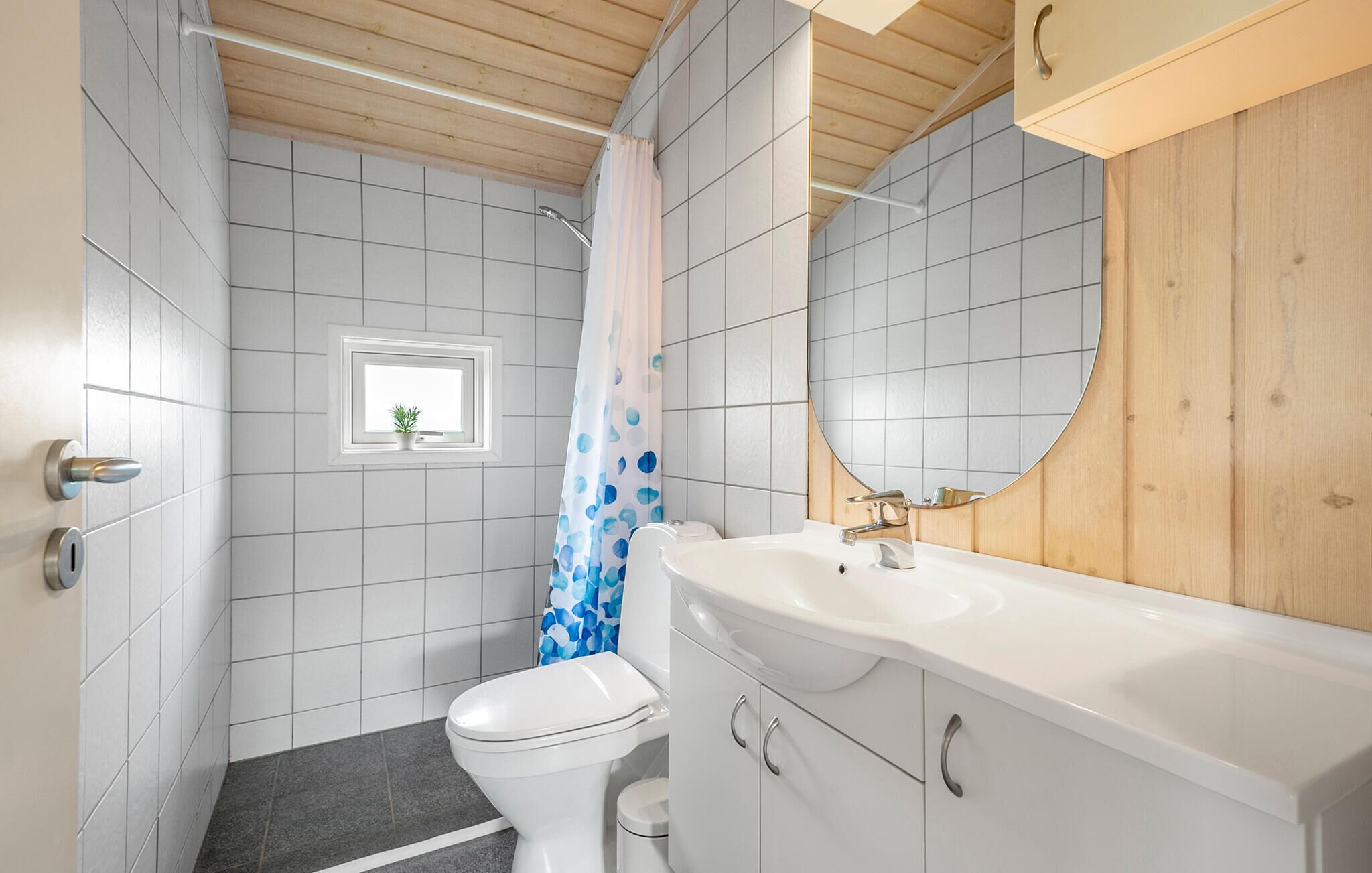 A bathroom with a toilet, a sink, a mirror, and a shower curtain.