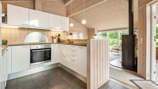 A modern kitchen with white cabinets, a built-in oven, and a large window.