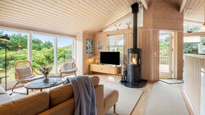 A cozy living room with a fireplace, large windows, and a comfortable seating area.