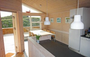 Enjoy meals in this kitchen with a dining table and chairs, refrigerator, and pendant light.