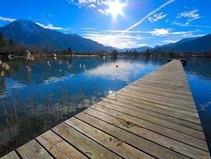 A wooden dock extending into a calm lake with mountains in the background.