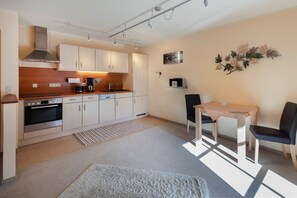 Una cocina compacta con electrodomésticos modernos, un comedor con dos sillas y un adorno de pared decorativo.