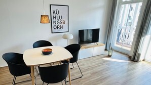 A modern living room with a dining area, a flat-screen TV, and a large window with curtains. - Barbarossa Whg B-12. - B-12 (Kühlungsborn)
