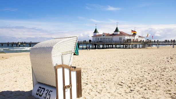 A beach chair labeled "80 35" on a sandy beach with a pier and buildings in the background. - Apartment 9 - Villa Meerblick - Ledwig, Villa Sea view (Heringsdorf)