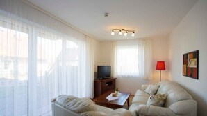 Un salon avec un canapé, une table basse, un téléviseur et une lampe.