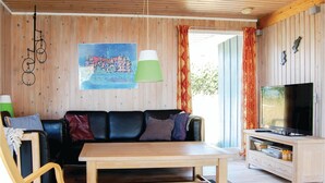 A cozy living room with a wooden ceiling, a black leather sofa, a wooden coffee table, a television, and a painting of a castle. - Amazing home in Hejls with kitchen (Hejls)