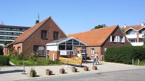A brick building with a covered outdoor seating area and a bench. - Steering Wheel 2 - Apartments House Steering Wheel (Esens)