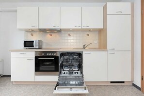 A kitchen with white cabinets, a microwave, an oven, and a dishwasher.