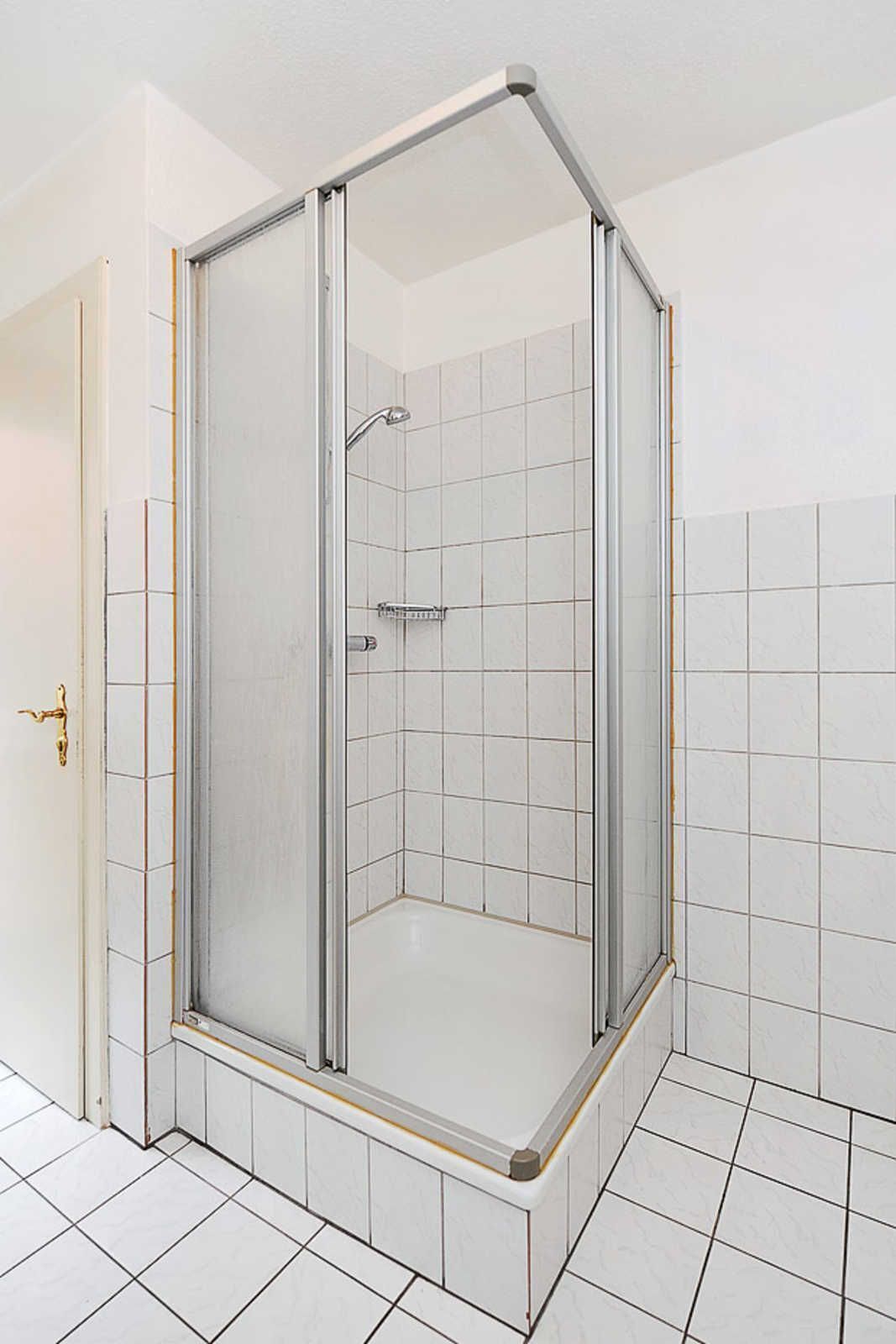 A glass-enclosed shower with a tiled floor and walls.