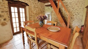 A rustic dining room with a wooden table, four chairs, a vase with flowers, and a bowl of grains. - Cozy home in Valreas with WiFi (Valreas)