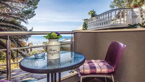 Un balcon avec une table en verre, une chaise et un vase rempli de fleurs.