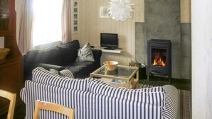 Una sala de estar acogedora con un sofá, una televisión, una chimenea y un adorno de pared.