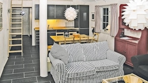 Un espacio habitable compacto con sofá, mesa de comedor y zona de cocina.