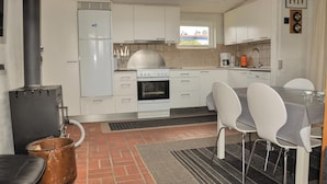 A compact kitchen with white cabinets, a stove, and a refrigerator. There is a dining table with chairs and a rug on the floor. - 3 bedroom awesome home in Faaborg (Faaborg)