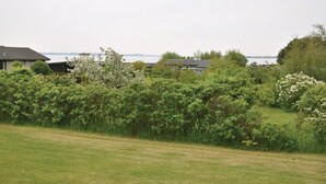 A residential area with houses, a grassy field, and a body of water in the background. - 3 bedroom awesome home in Faaborg (Faaborg)