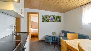 A compact living space with a kitchenette, a dining area, and a seating area with a blue sofa and a small round table.