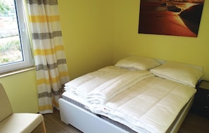 A small, neatly made bed with white bedding in a room with yellow walls. - Beautiful apartment in Boiensdorf with sauna (Boiensdorf)