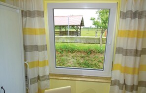 A room with a window overlooking a fenced area with a building and trees. - Beautiful apartment in Boiensdorf with sauna (Boiensdorf)