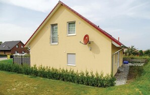 Una casa de un piso con techo rojo, una antena parabólica y una ventana pequeña.