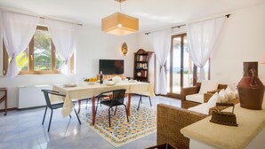 A dining area with a table set for two, a television, and a bookshelf.