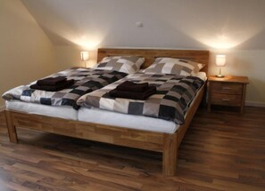 A single bed with a wooden frame, two bedside tables, and a sloped ceiling.
