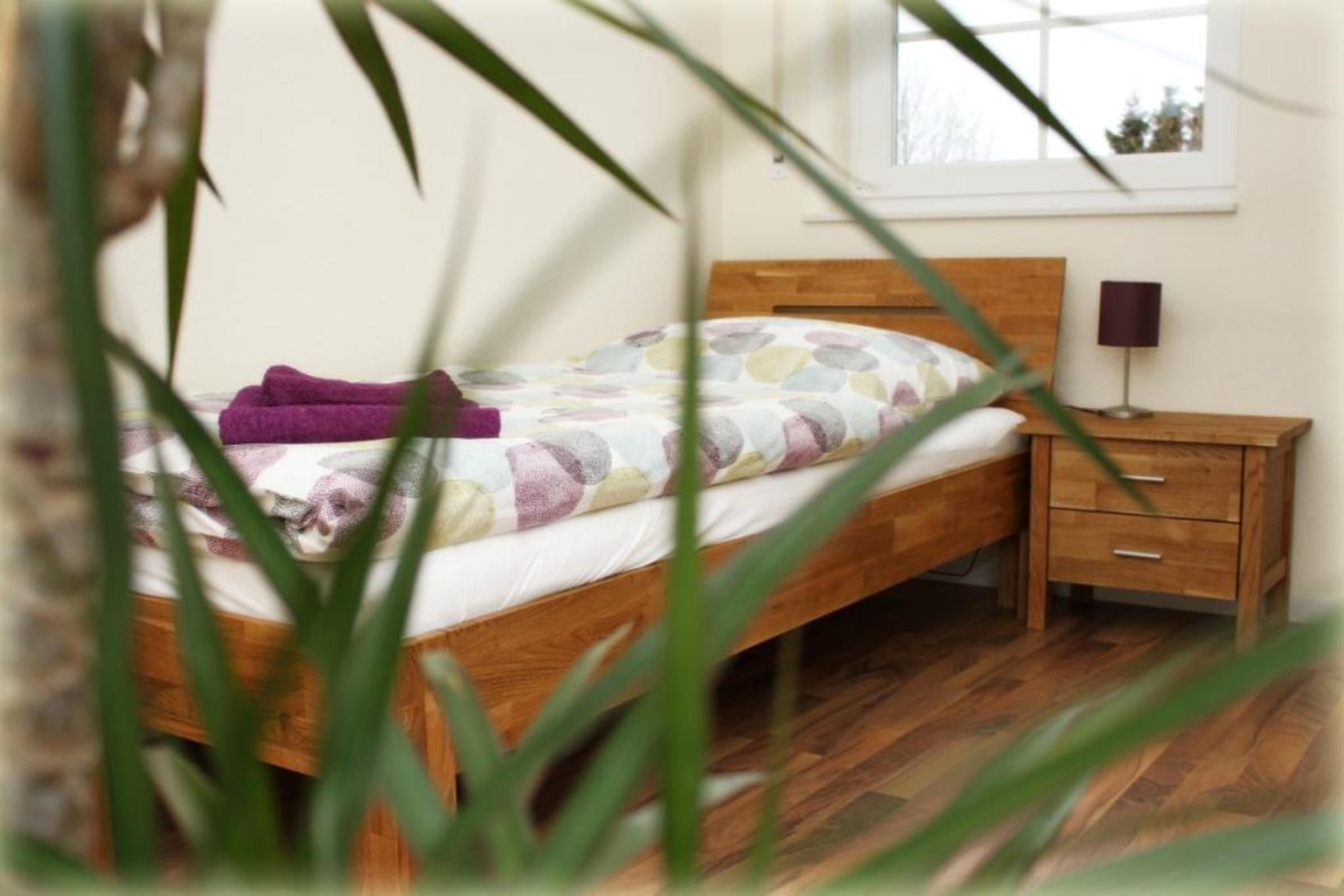 Quarto com cama de madeira, mesa de cabeceira com abajur e janela com vista.