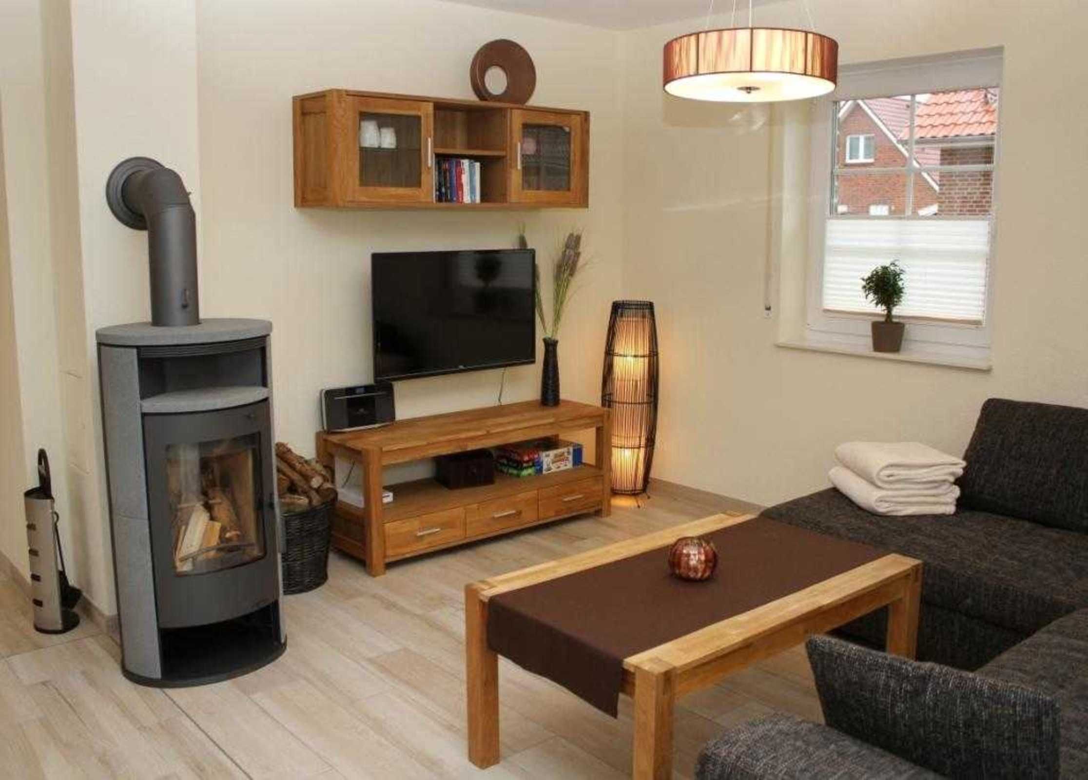 Een woonkamer met een open haard, televisie, een houten tv-meubel en een bank.