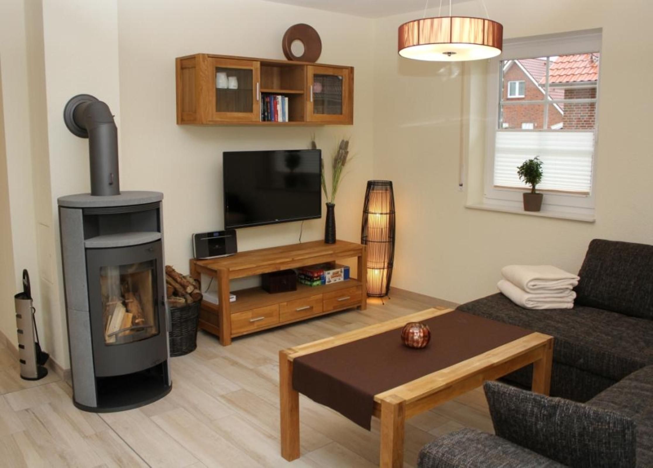 A living room with a fireplace, television, wooden entertainment unit, sofa, and a table.