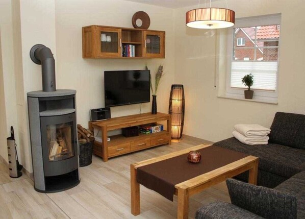 A living room with a fireplace, TV, wooden entertainment unit, and a sofa.