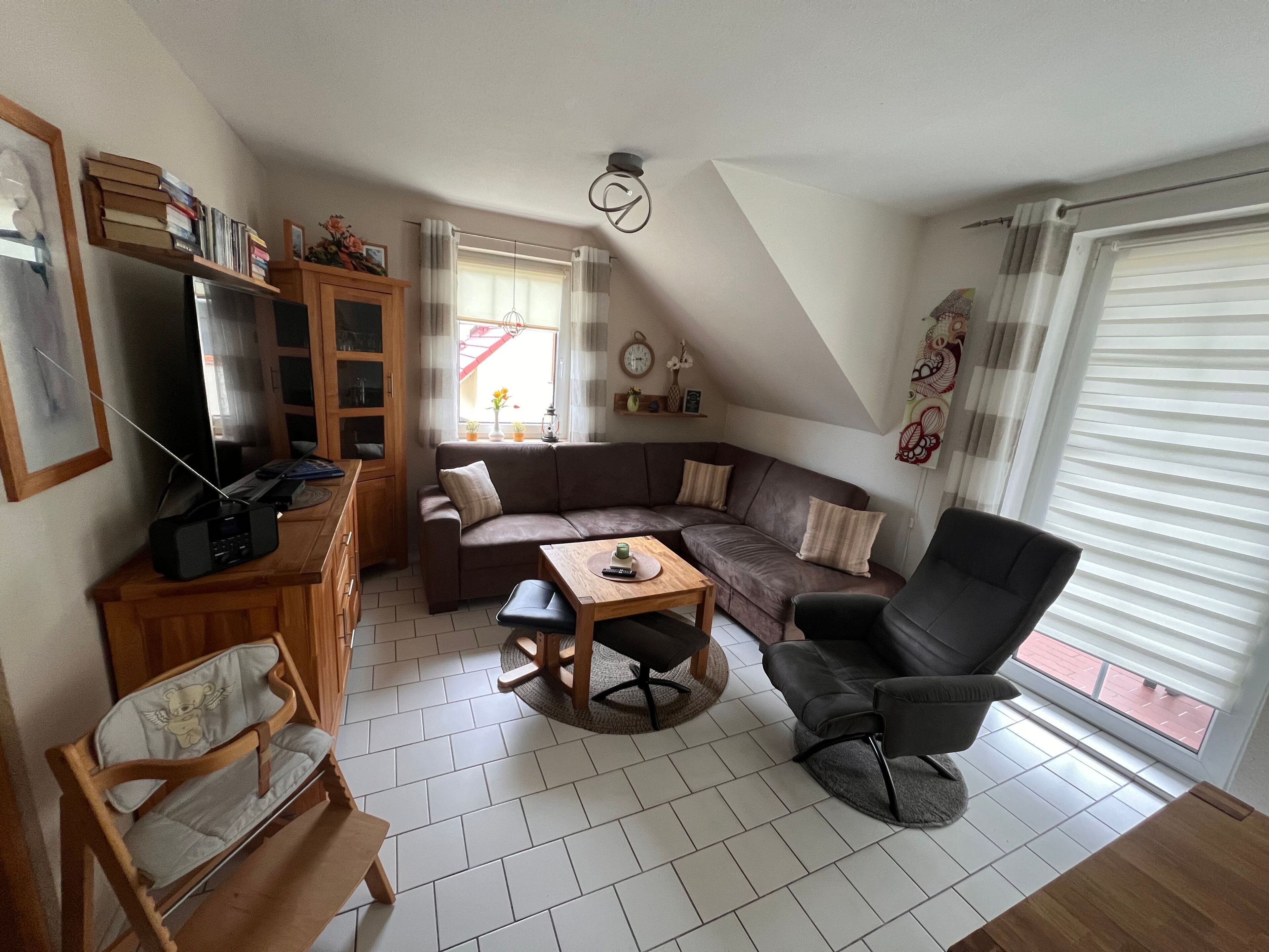 Ein Wohnzimmer mit einer Couch, einem Esstisch, einem Fernseher und einem Sessel.