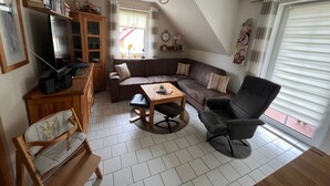 Un salon avec un canapé, une table à manger, un téléviseur et un fauteuil.