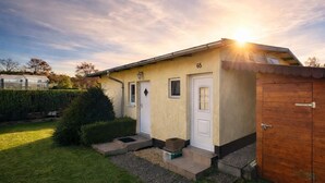 Un bâtiment d’un seul étage, avec le numéro « 65 » sur la façade, un petit porche et une remise en bois sur le côté droit.