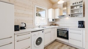 Una cocina moderna con muebles blancos, una lavadora Siemens, un horno Bosch y una cafetera.