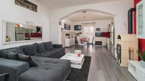 Una sala de estar moderna con un sofá gris, una mesa de centro blanca y una cocina al fondo.