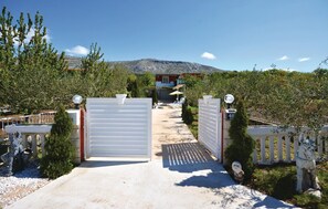 Enter a serene oasis through the beautifully landscaped entrance, featuring a white gate with a decorative finial and a sign indicating the property number.