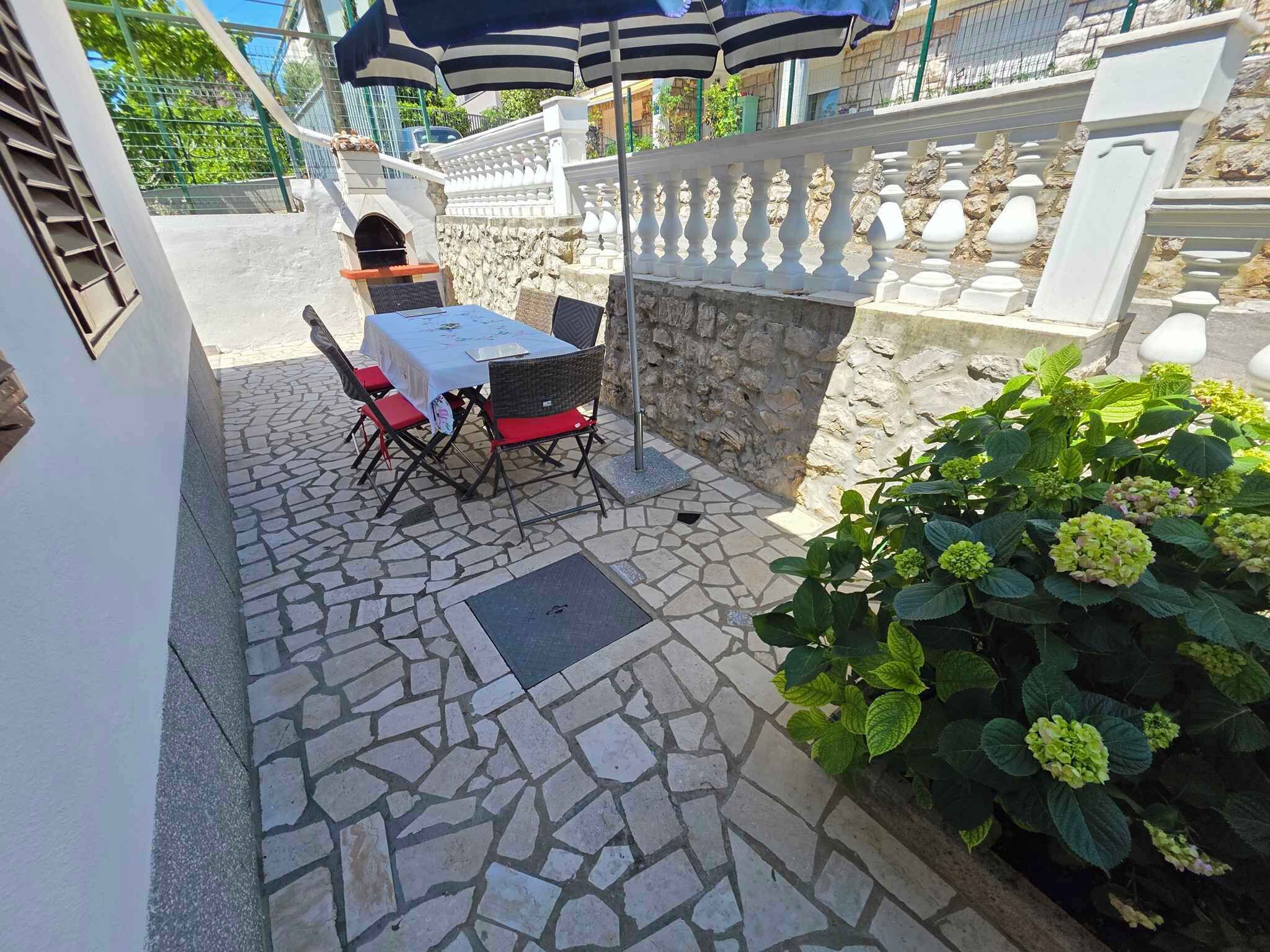 A patio with a stone floor, a table with chairs, and a potted plant.