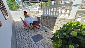 A patio with a stone floor, a table with chairs, and a potted plant. - Holiday apartment 100 m from the beach (Crikvenica)