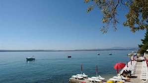 A calm lake with boats, a row of sun loungers, and a clear sky. - Holiday apartment 100 m from the beach (Crikvenica)