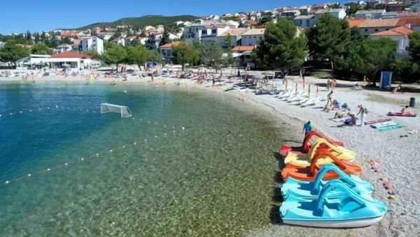 A beach with clear water, a row of colorful inflatable boats, and a row of umbrellas. - Holiday apartment 100 m from the beach (Crikvenica)
