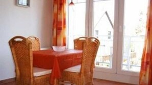 A dining area with a red table and four wicker chairs.
