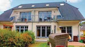 A two-story house with a balcony, large windows, and a garden area.