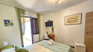 Een hotelkamer met twee bedden, een bureau met stoel, een televisie en een deur.